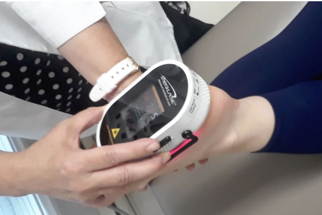 A cold laser being applied to a patient's knee