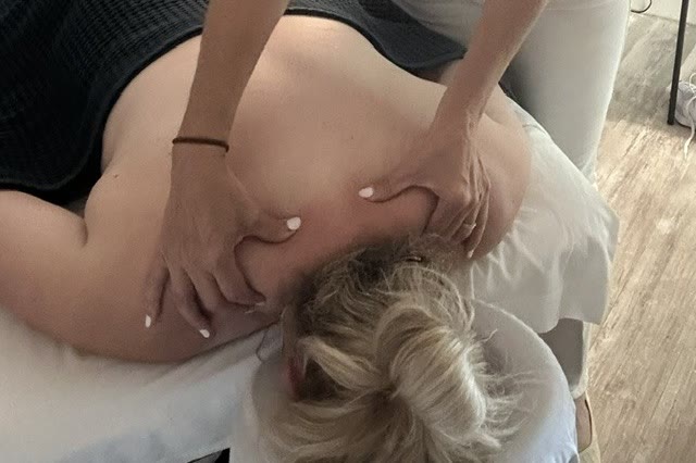 A registered massage therapist working on a client's shoulders at Synergy