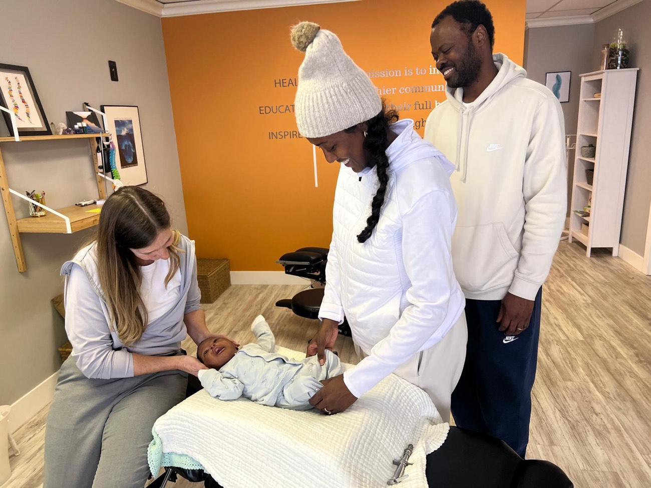 Dr. Shelley giving an infant a gentle adjustment while the parents look on at Synergy Chiropractic